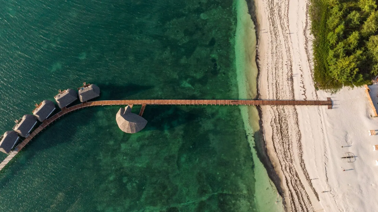 Lodges on stilts above a turquoise lagoon